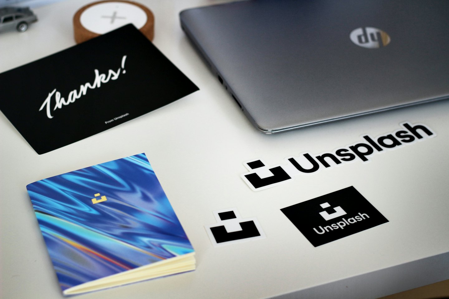 Branded laptop stickers and notebooks arranged on a white desk.